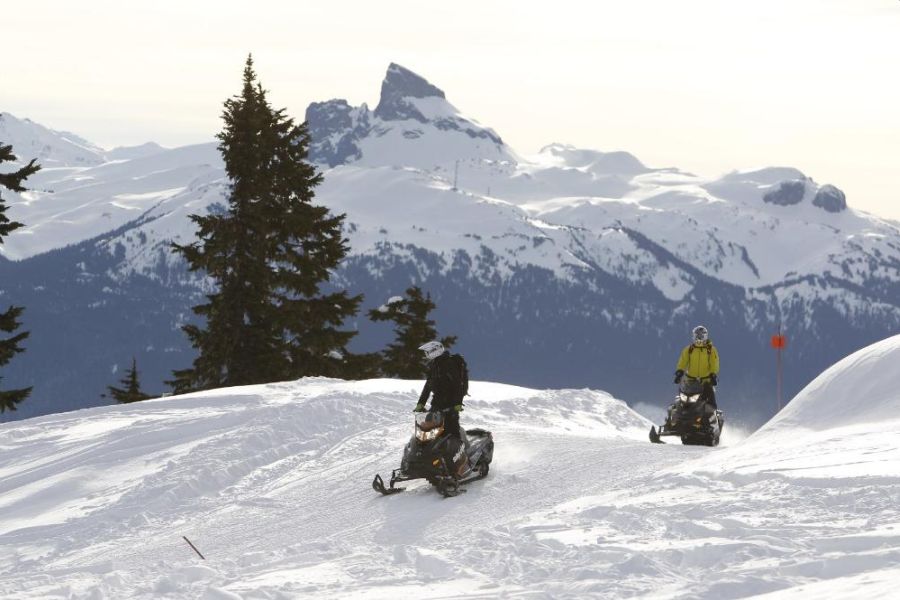 Twee mensen op sneeuwscooters tijdens een sneeuwscootertocht in Whistler in Canada.