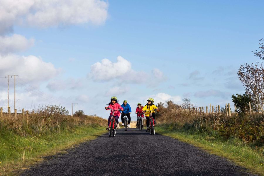 Vier mensen op een fiets over de weg in Ierland