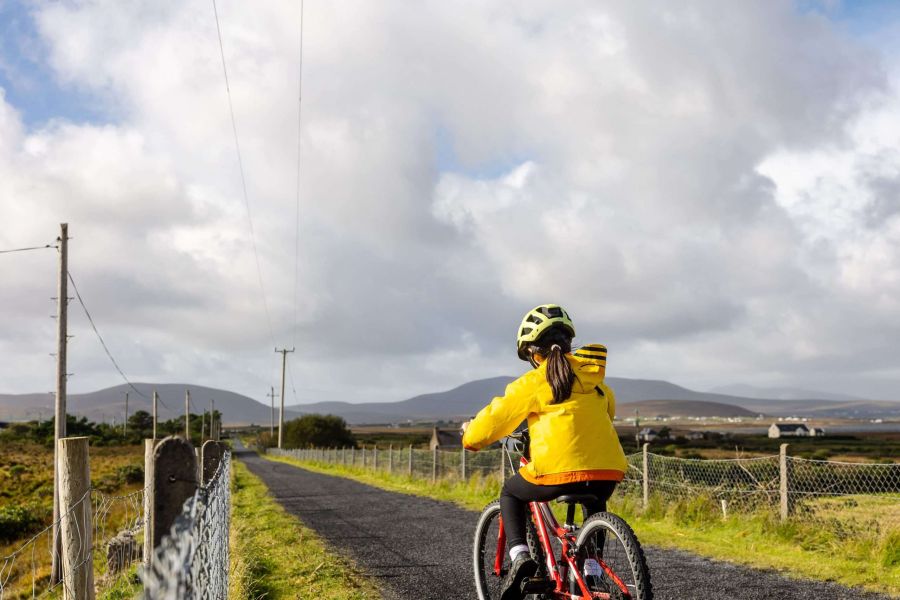 Kind met gele jas op een rode fiets in Ierland